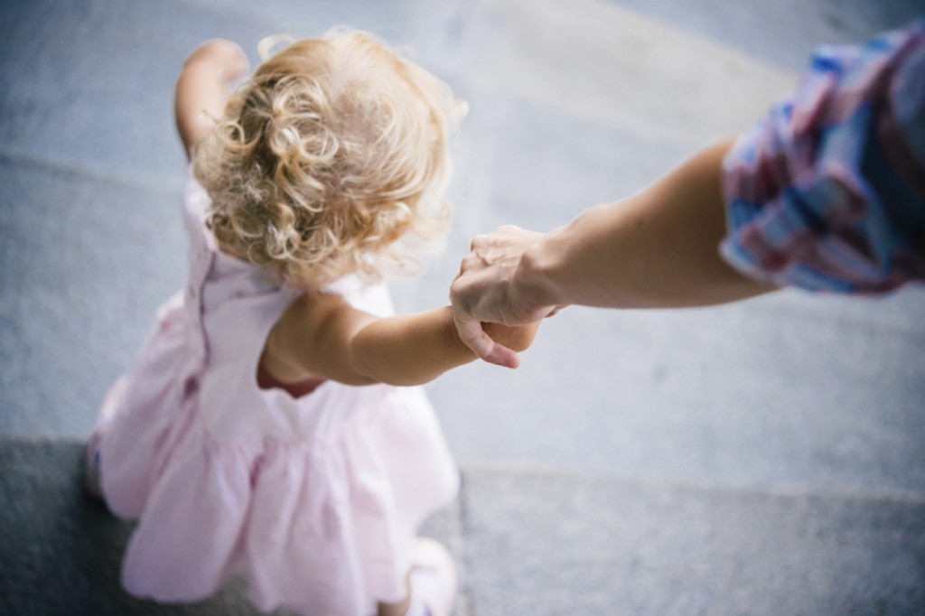 Mother holds her daughter's hand during a walk outdoors