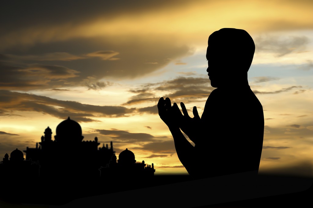 Silhouette muslim people praying at sunset.