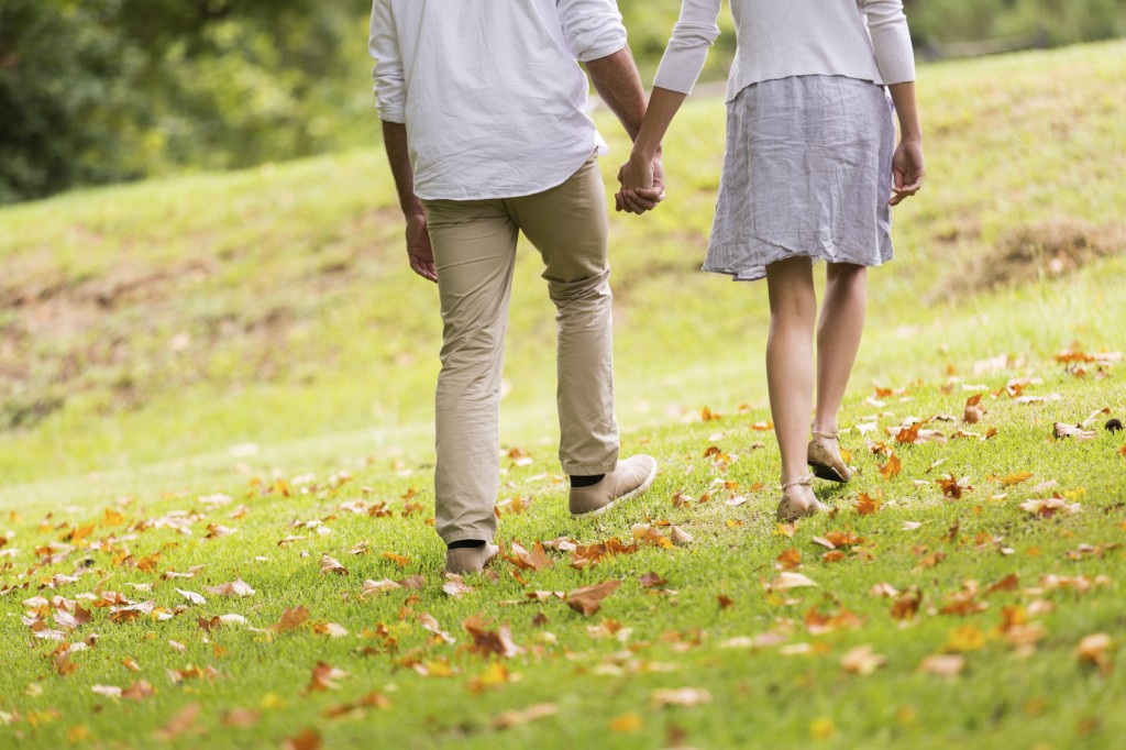 young couple holding hands walking in park