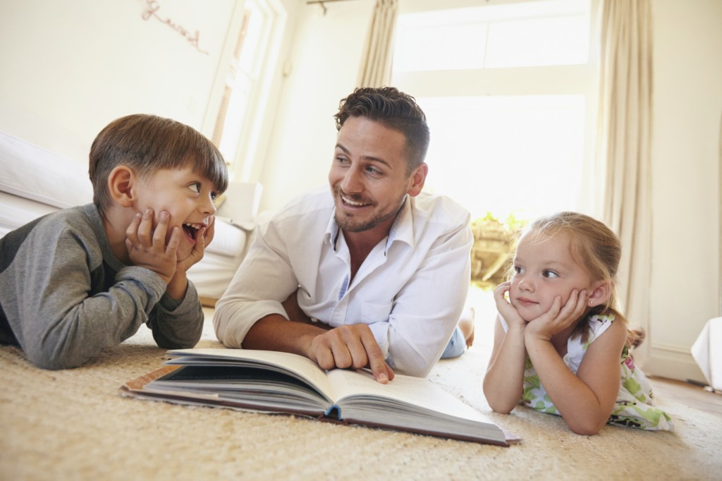 Happy young family lying on the floor reading a book