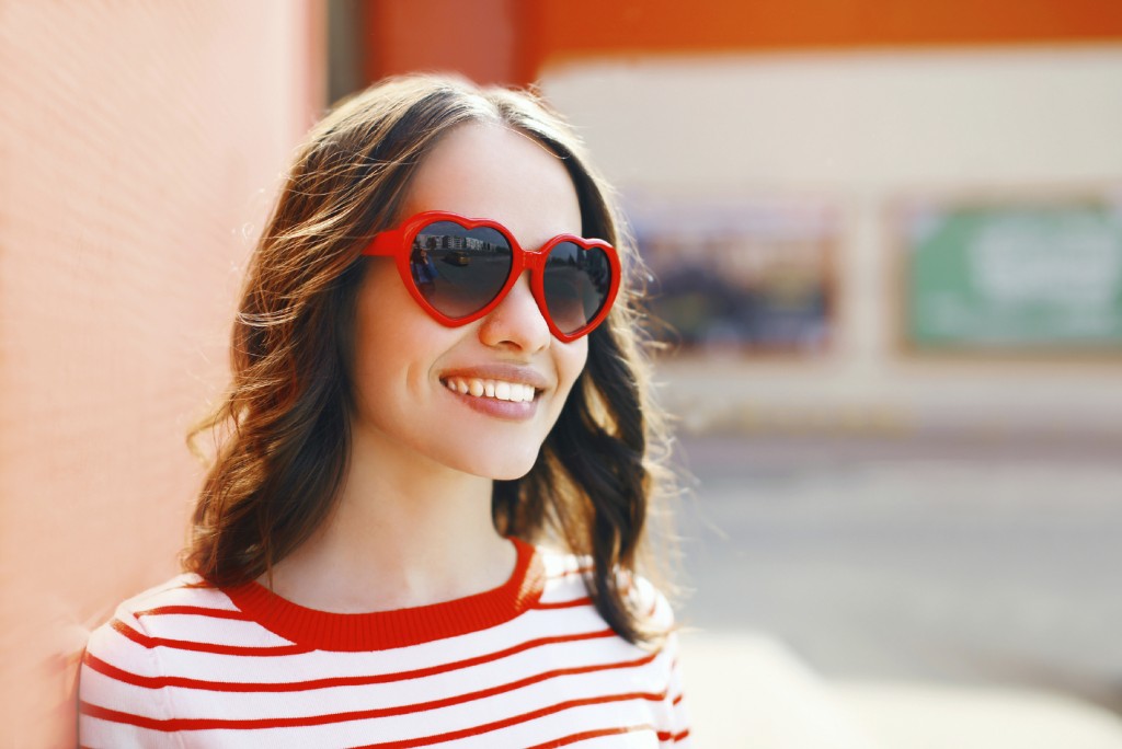 Portrait of pretty smiling woman in red sunglasses outdoors