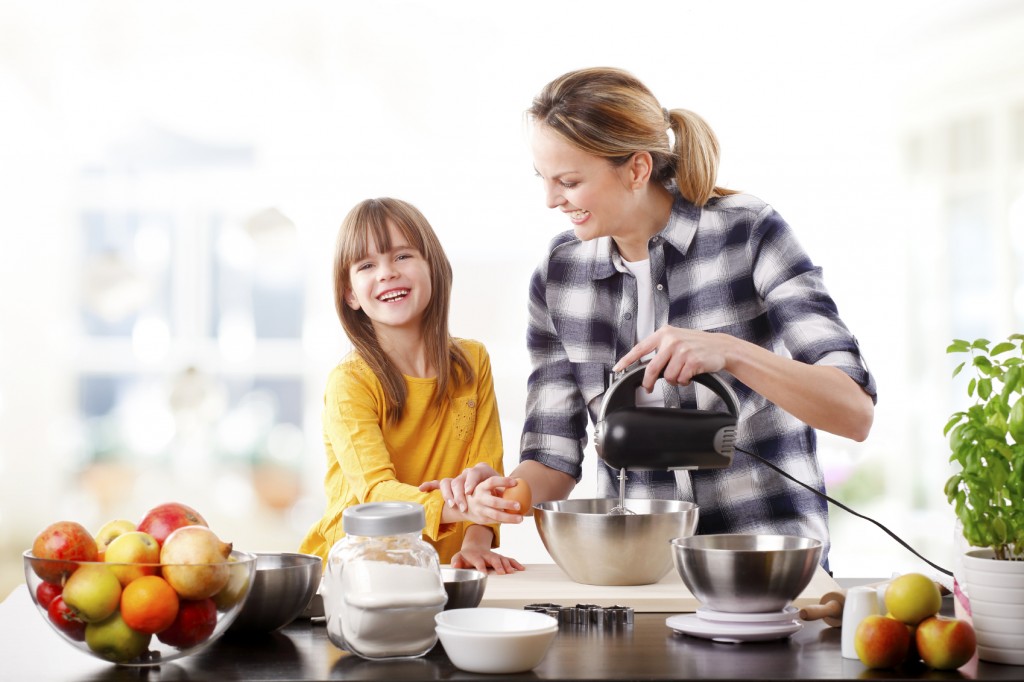 Portrait of adorable little girl and her mother baking together at home.