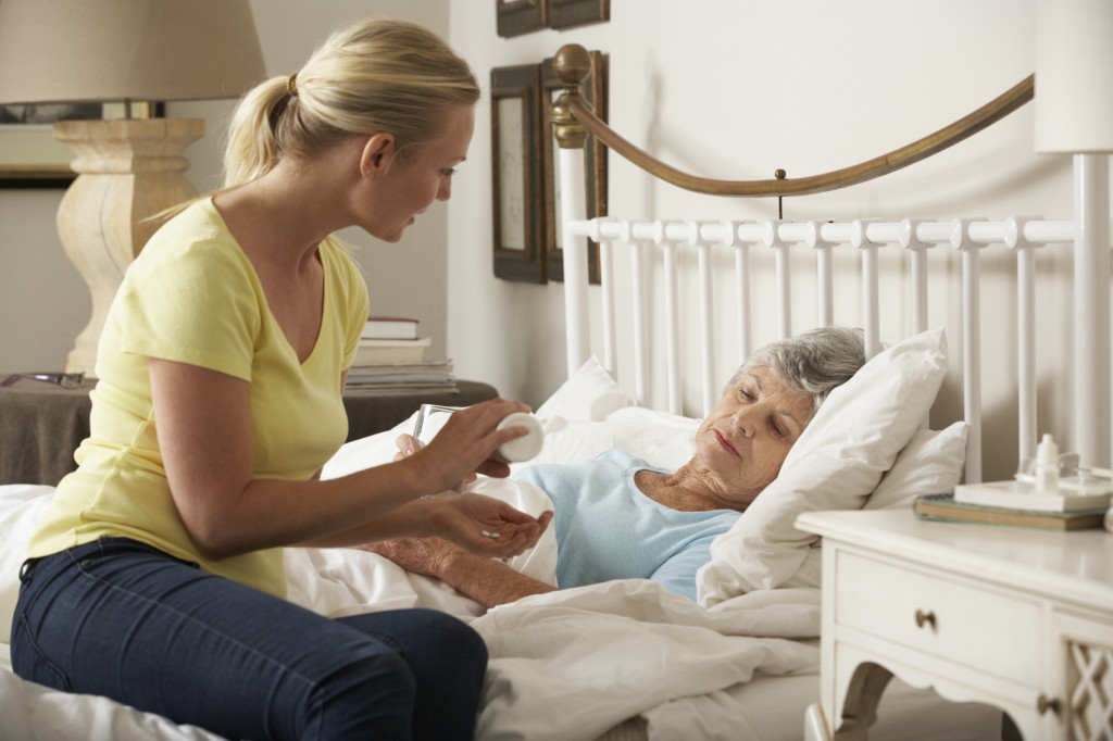 Adult Daughter Giving Senior Female Parent Medication In Bed