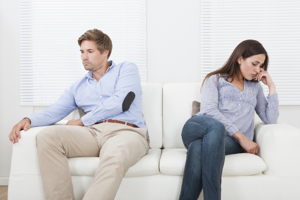 Couple sitting on a couch ignoring each other