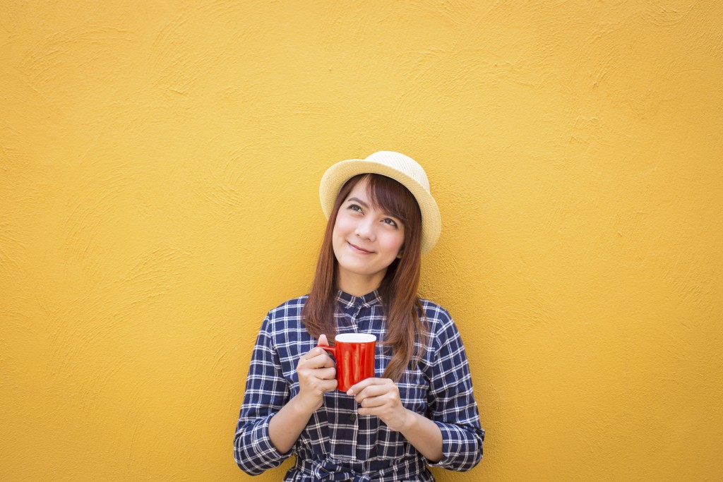 smiling woman wear in dress and hat holding red cup