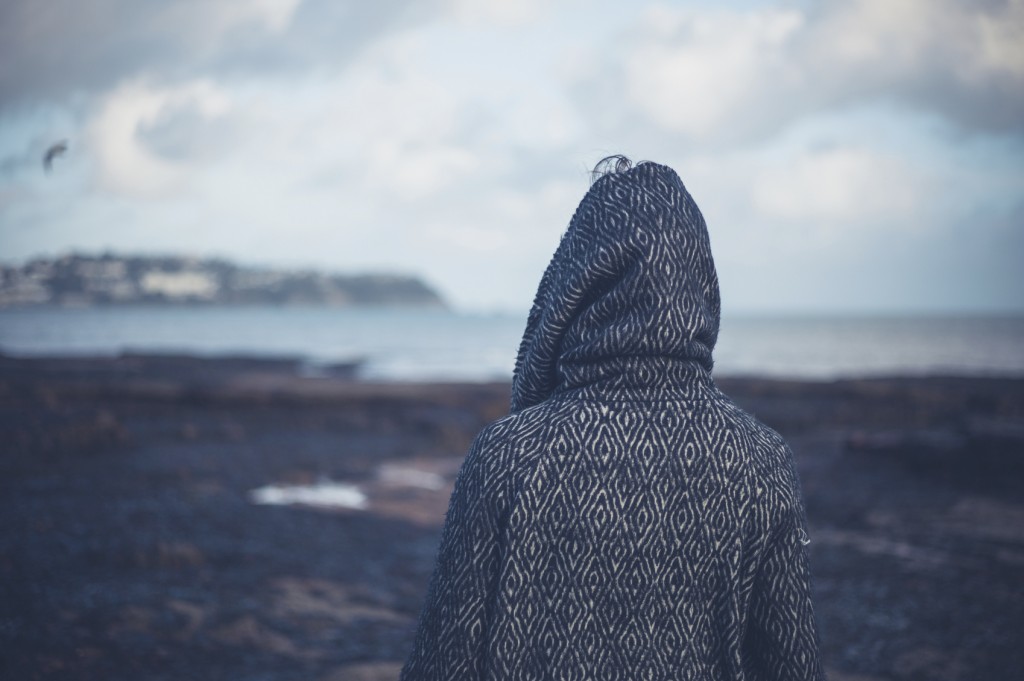 Young woman in hooded coat walking on beach
