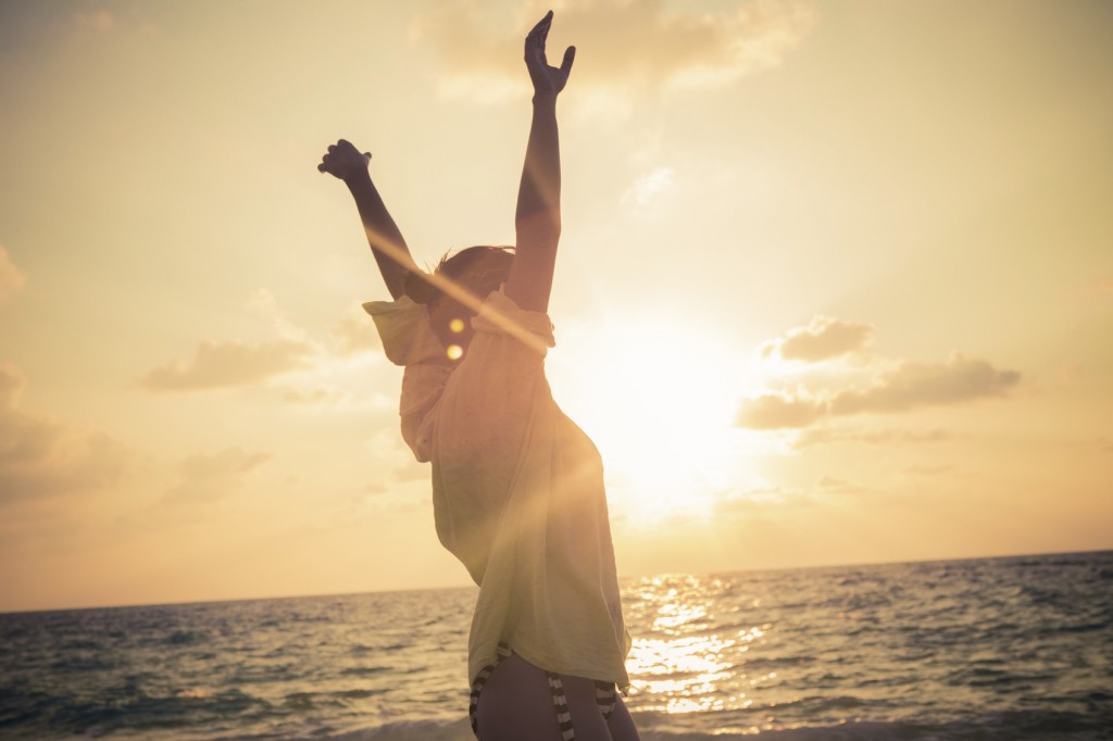 Young woman standing on beach with her arms outstretched