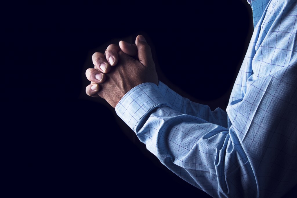 Men in prayer on dark, religious concept.