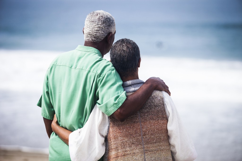 Senior African American couple together on the beach, from behind.