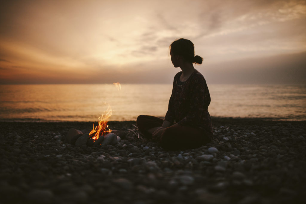 Girl sitting near the fireplace on the beach