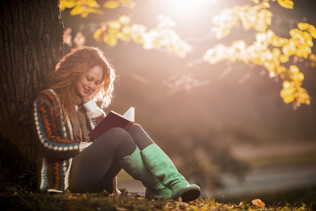 Young woman relaxing while reading a book at the park.