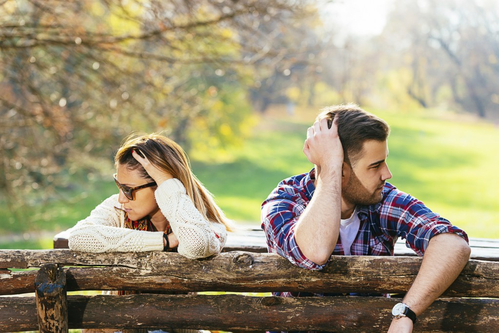Young attractive couple having relationship issues in park