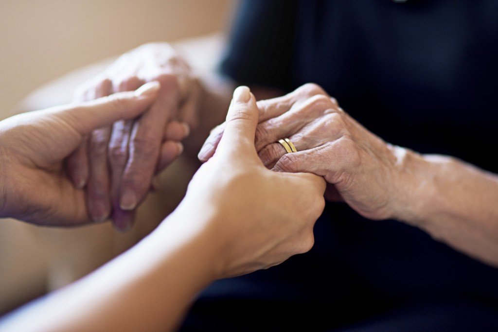 Cropped shot of a person holding an elderly woman’s hands
