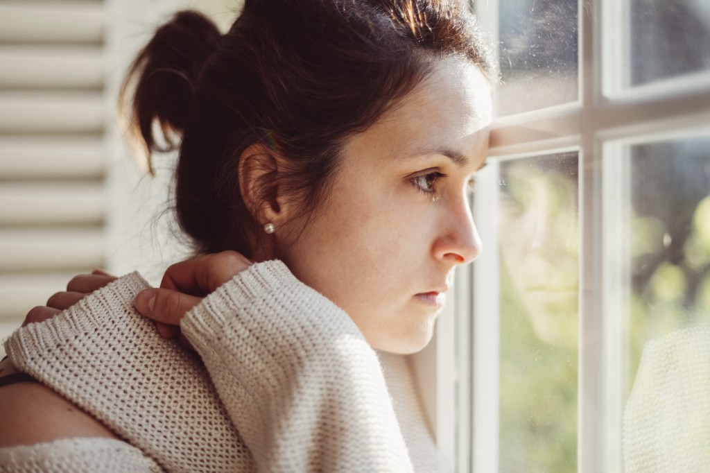 Depressed woman looking through window