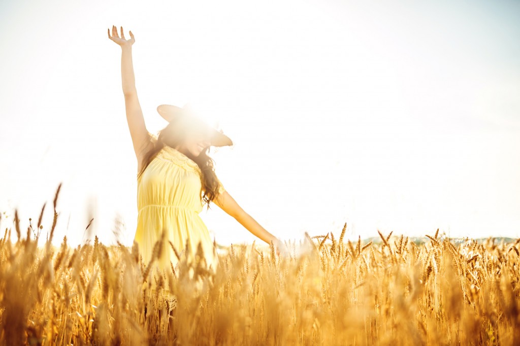 young woman enjoying on a wheat field on sunny summer day