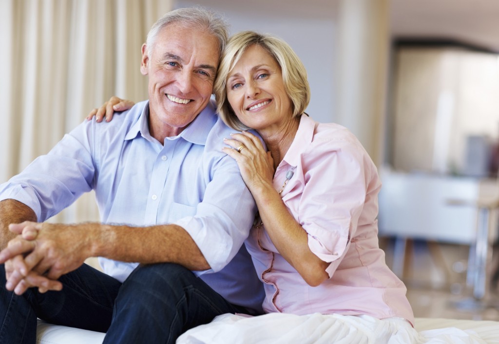 Portrait of happy senior couple sitting and smiling together at home
