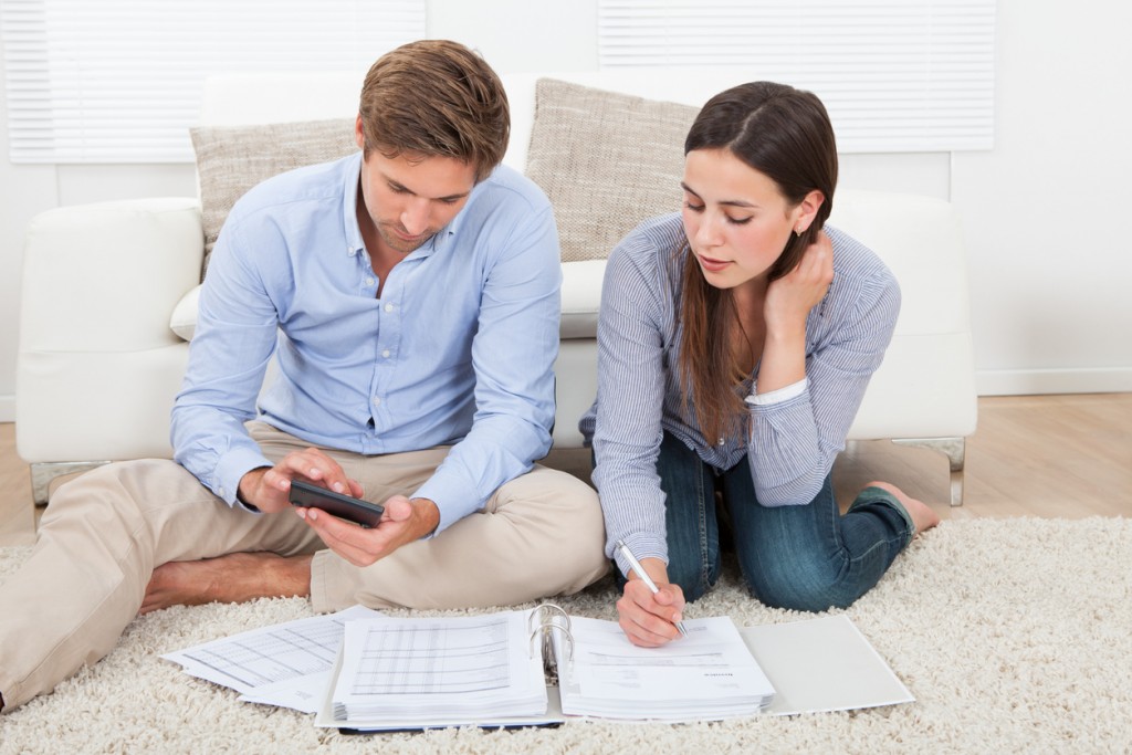 Full length of couple calculating budget in living room at home