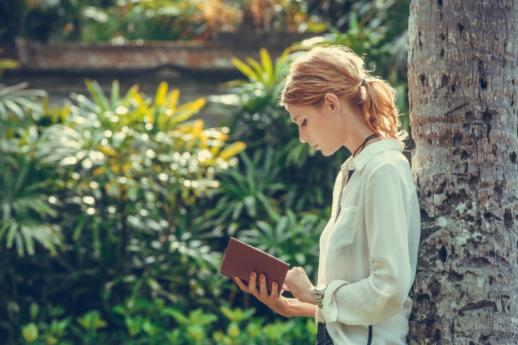 Portrait of a young woman reading a book in the park