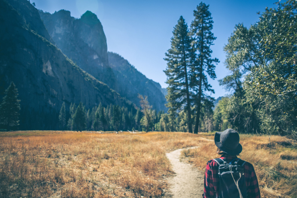 A shot of a young woman hiking down a path in a majestic landscape.