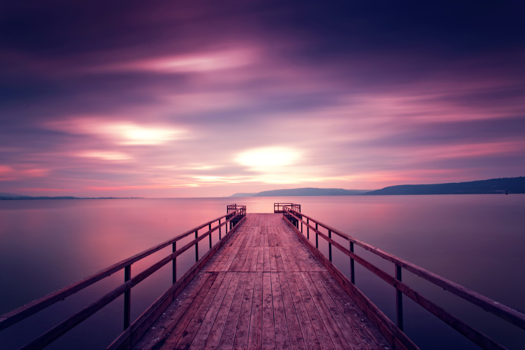 long exposue view of purple sky and wooden pier during sunset. reflections over sea. taken in Canakkale, Turkey.