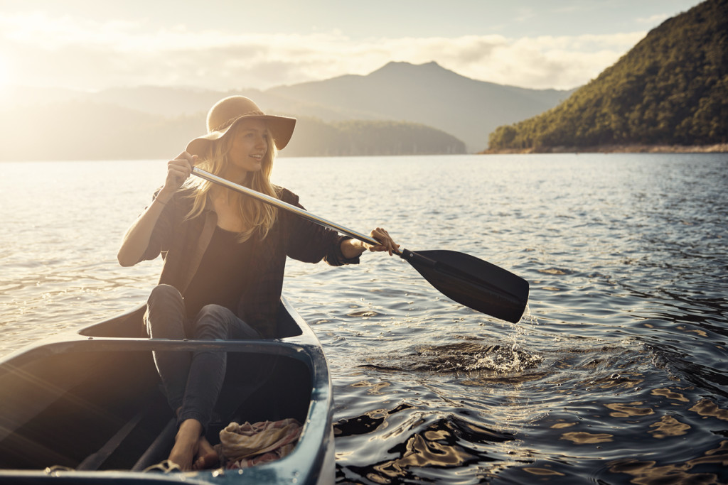 Shot of a young woman rowing a boat out on the lake