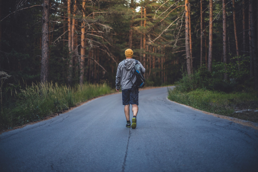 Backpacker walks alone by the road in forest