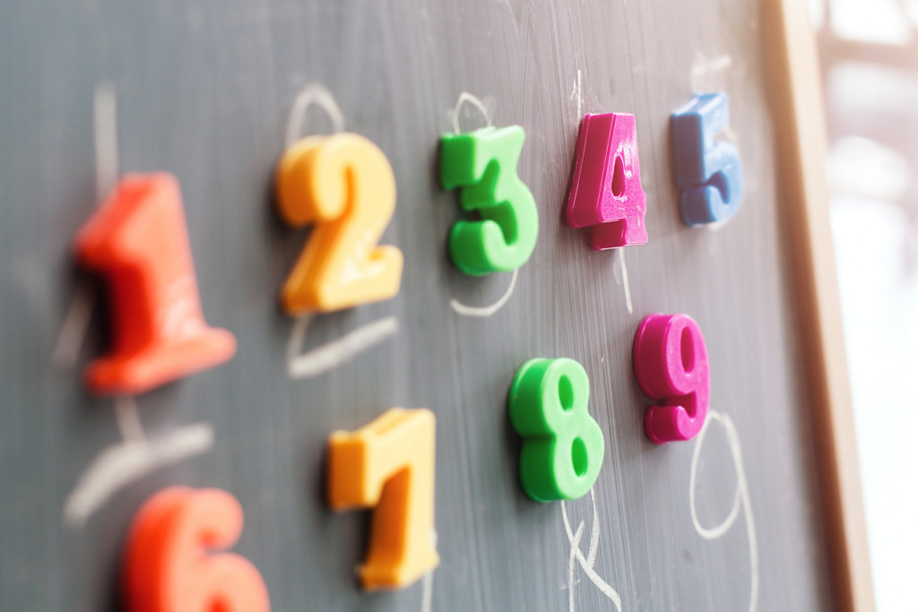 Multiple colorful magnets with numbers on a blackboard.