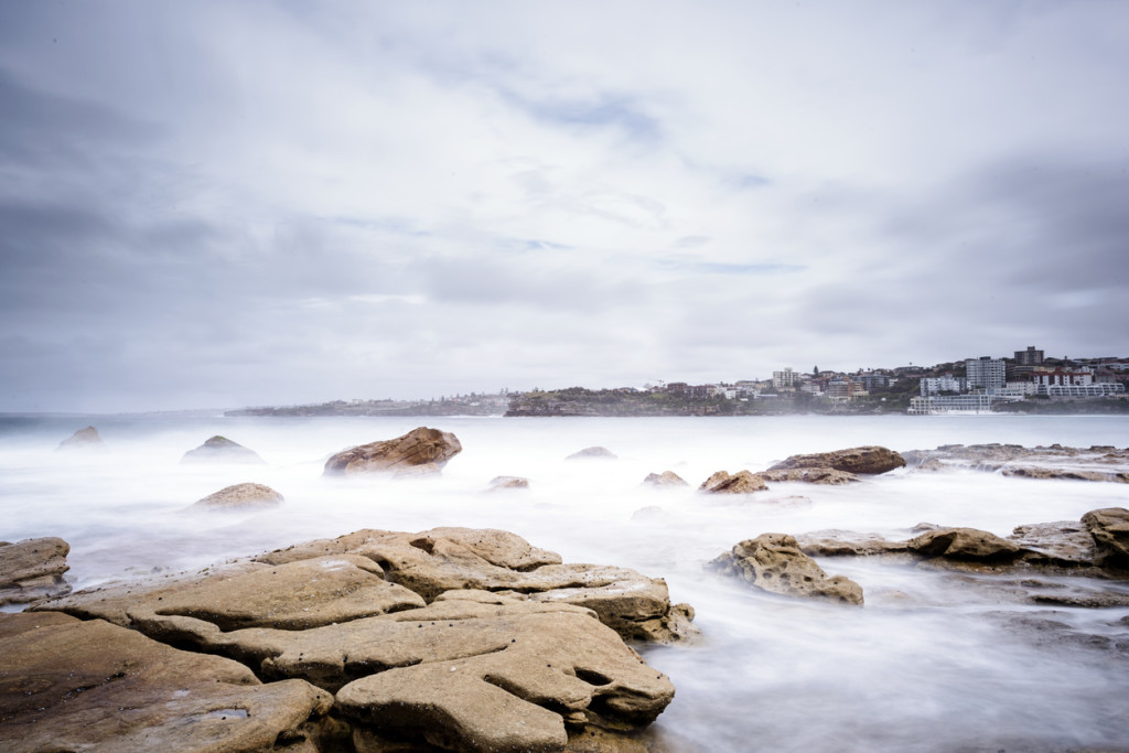 Landscape of mist over rocks in the sea on a cloudy stormy day in Sydney Australia.