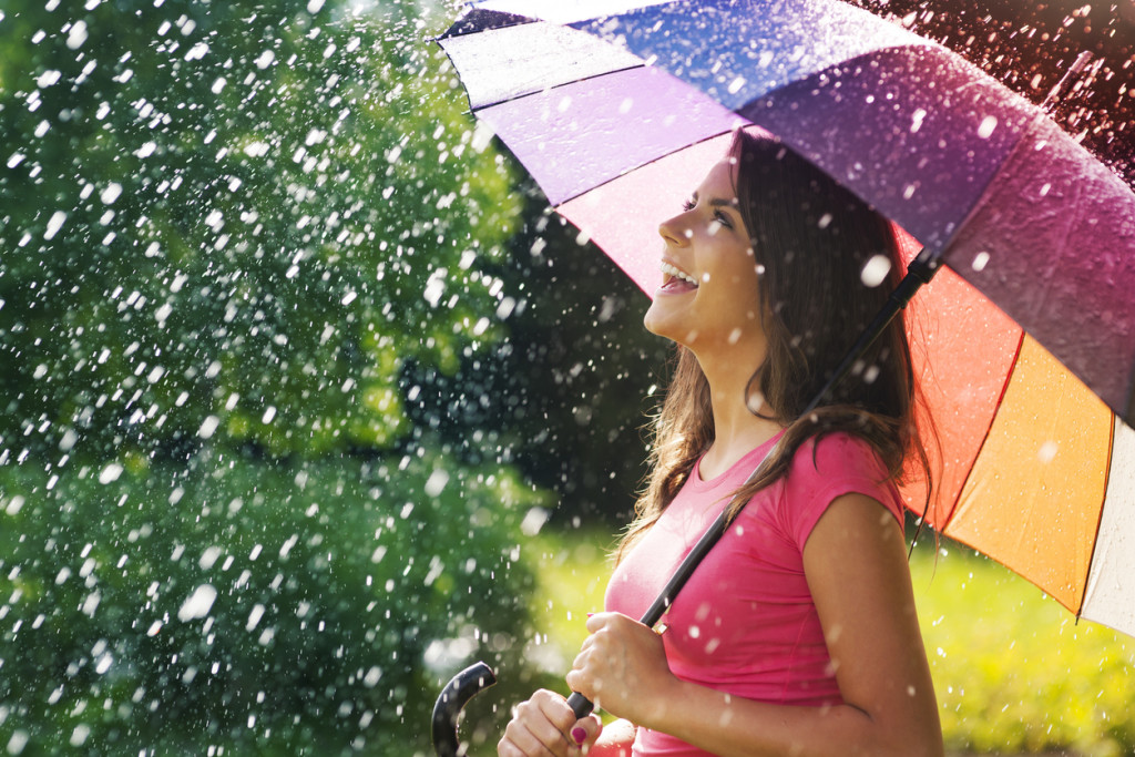 woman laughing with umbrella in rain and sunshine