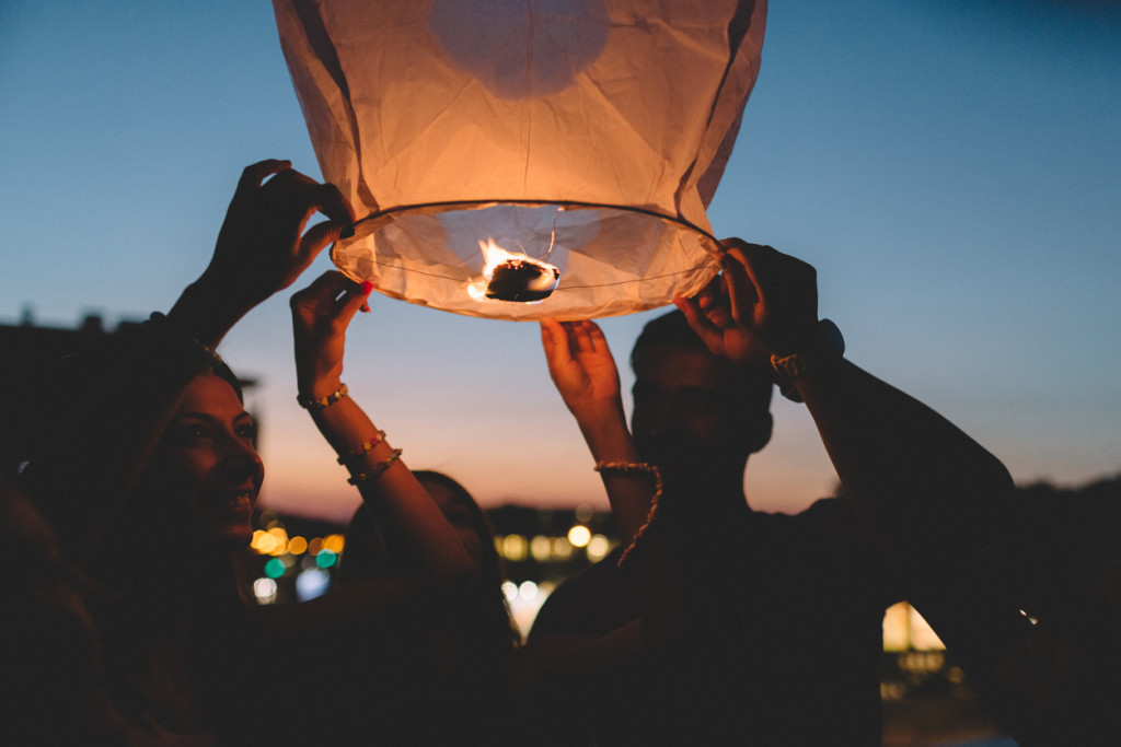 Friends releasing paper lantern in the sky at night