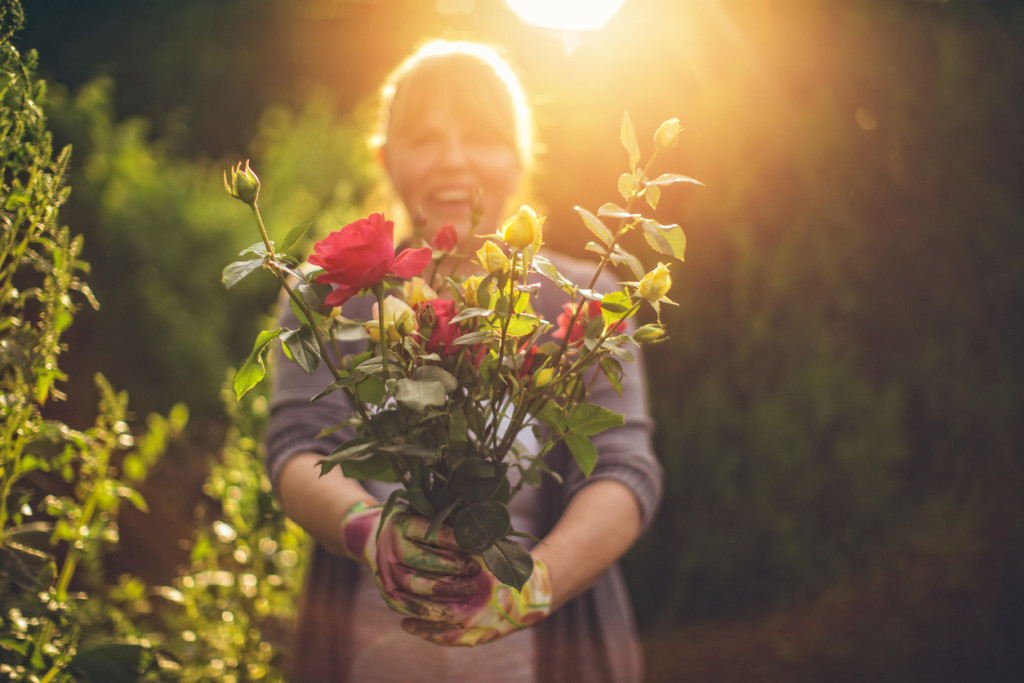 Portrait of smiling mid-adult woman who is proudly presenting flowers from her garden
