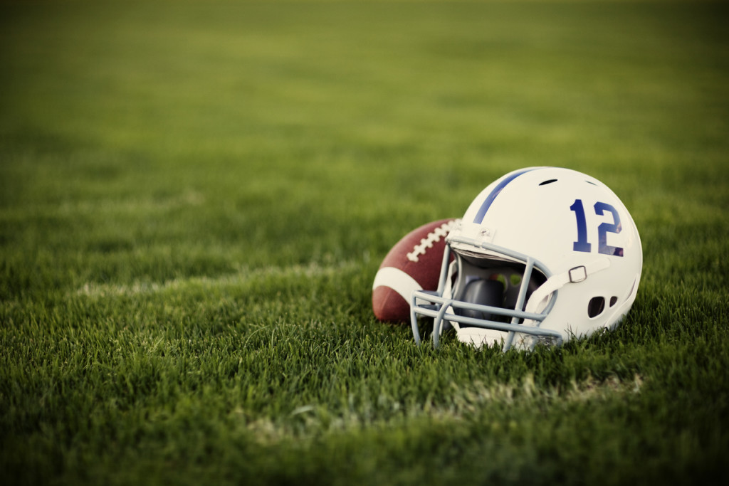 A vintage style American football helmet and football on the football field.
