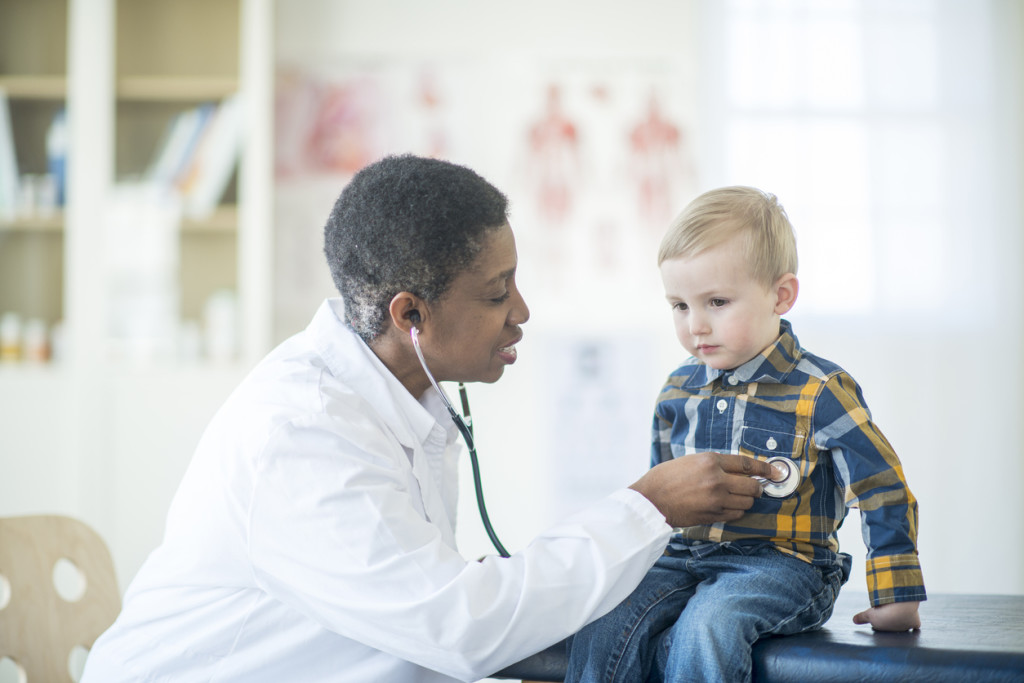 A female doctor is listening to a little boy's heartbeat at the doctor's office.