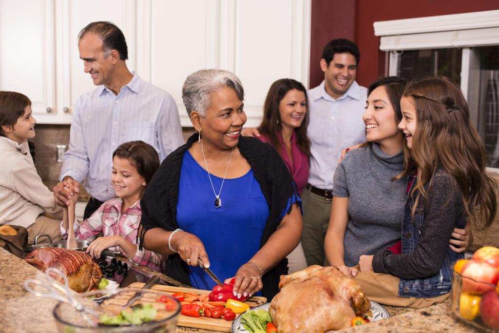 Multi-ethnic group prepare dinner together in home kitchen