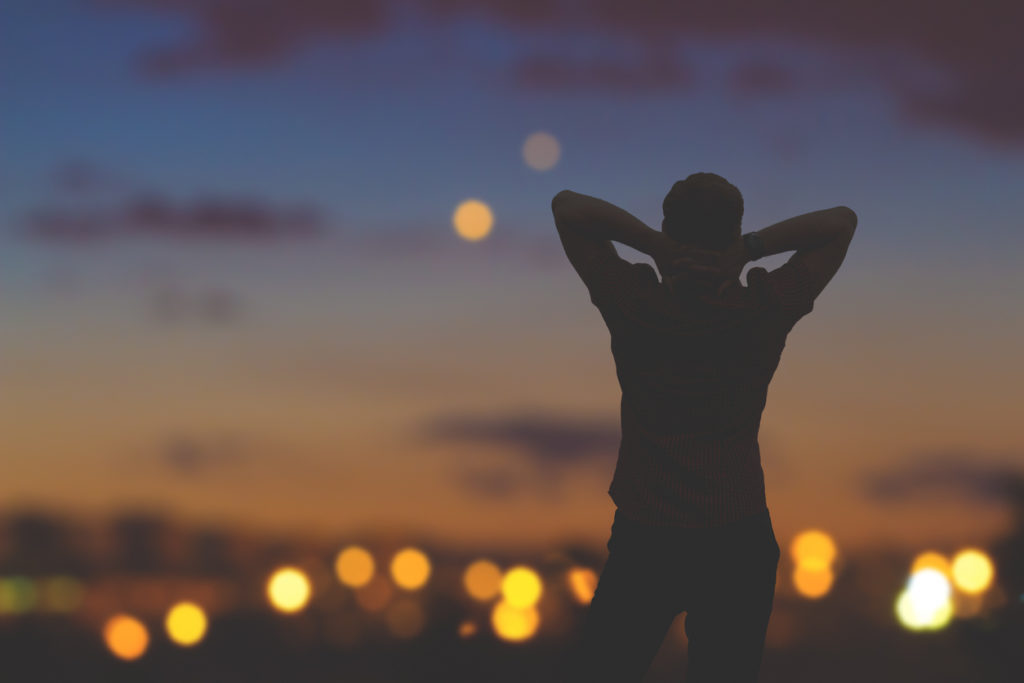 Silhouette of a man with city lights in the background.