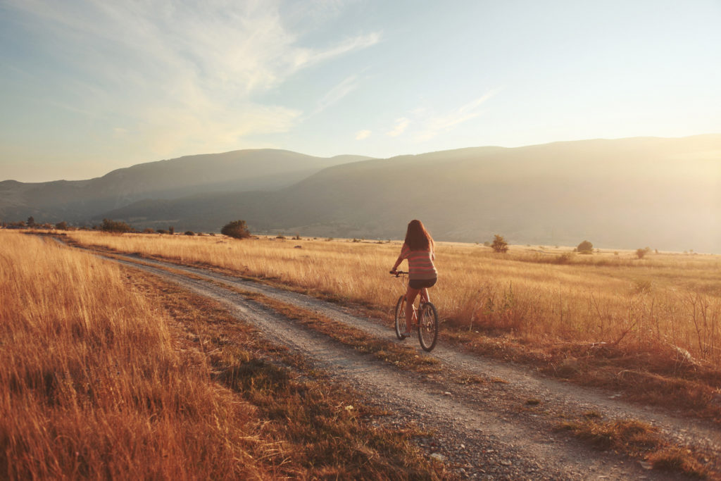 vintage toned young brunette on a bicycle, lit by the Autumn sunset.