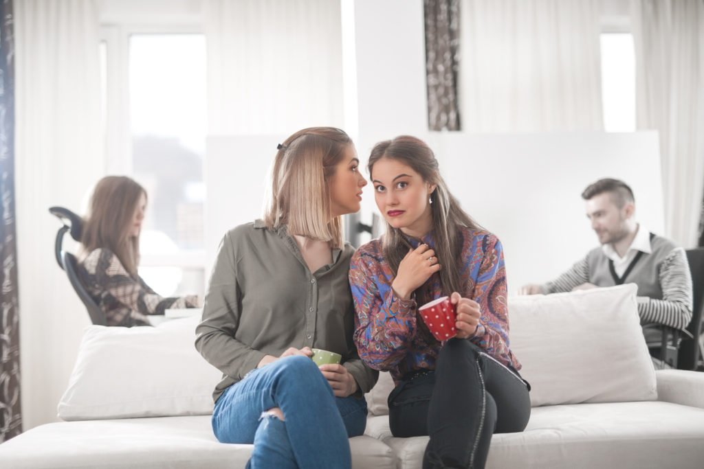 Two young businesswomen are having a coffee and gossip break in the office
