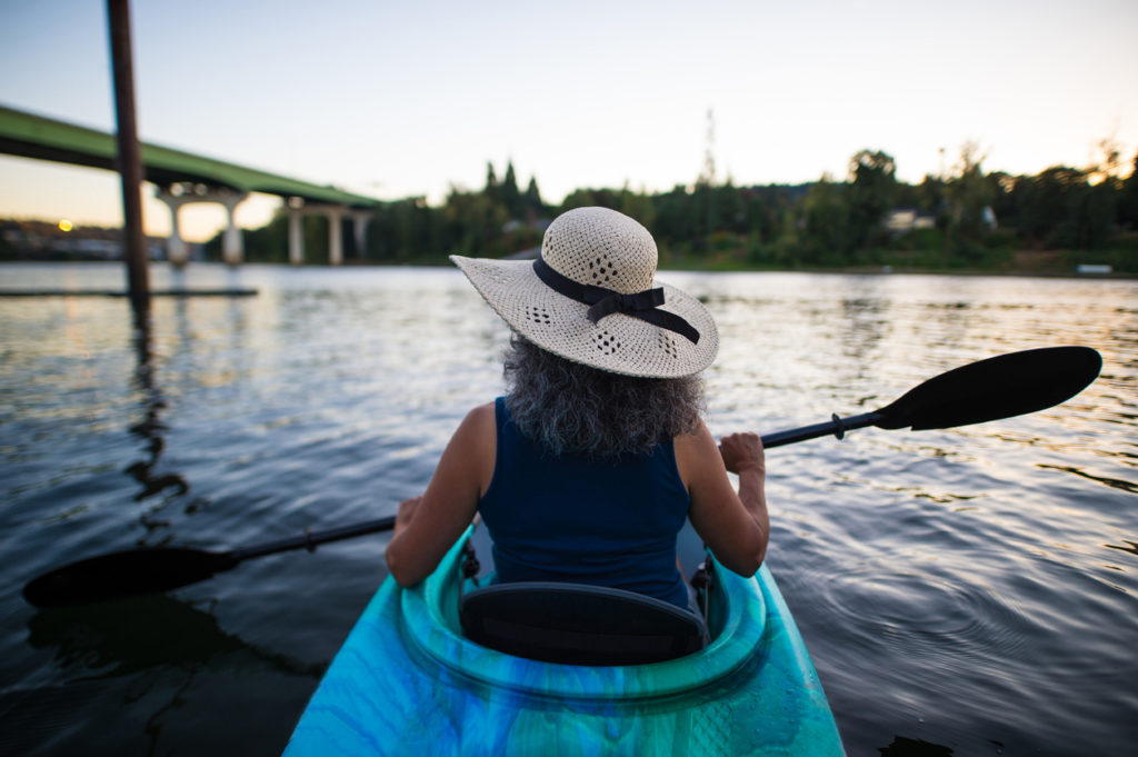 Ethnic female senior citizen kayaks in river