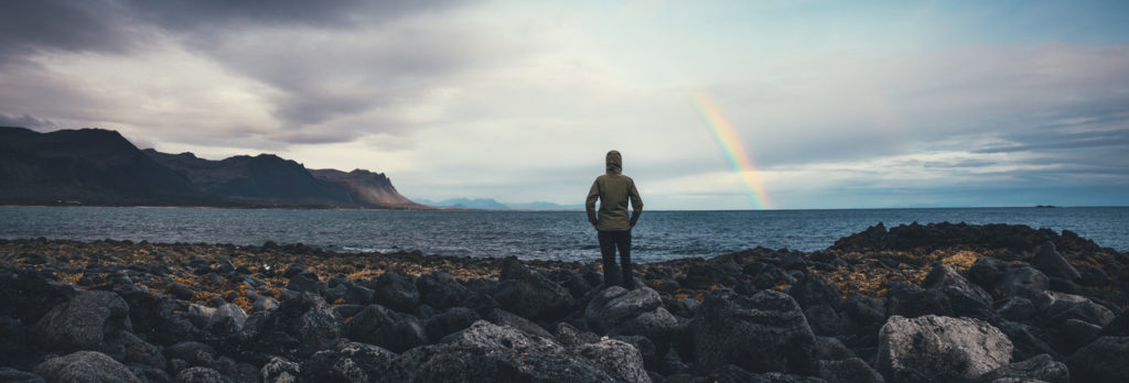 Woman watching rainbow over Icelandic landscape at Snaefellsnes peninsula (west parth of the island).