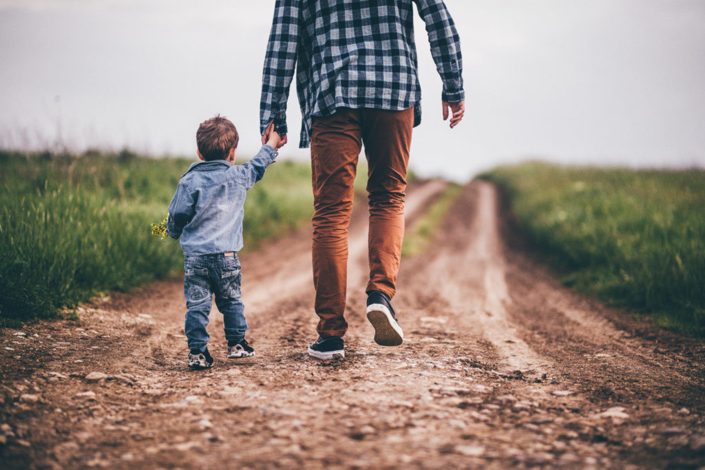 Father and son walking on an emoty country road and holding hands