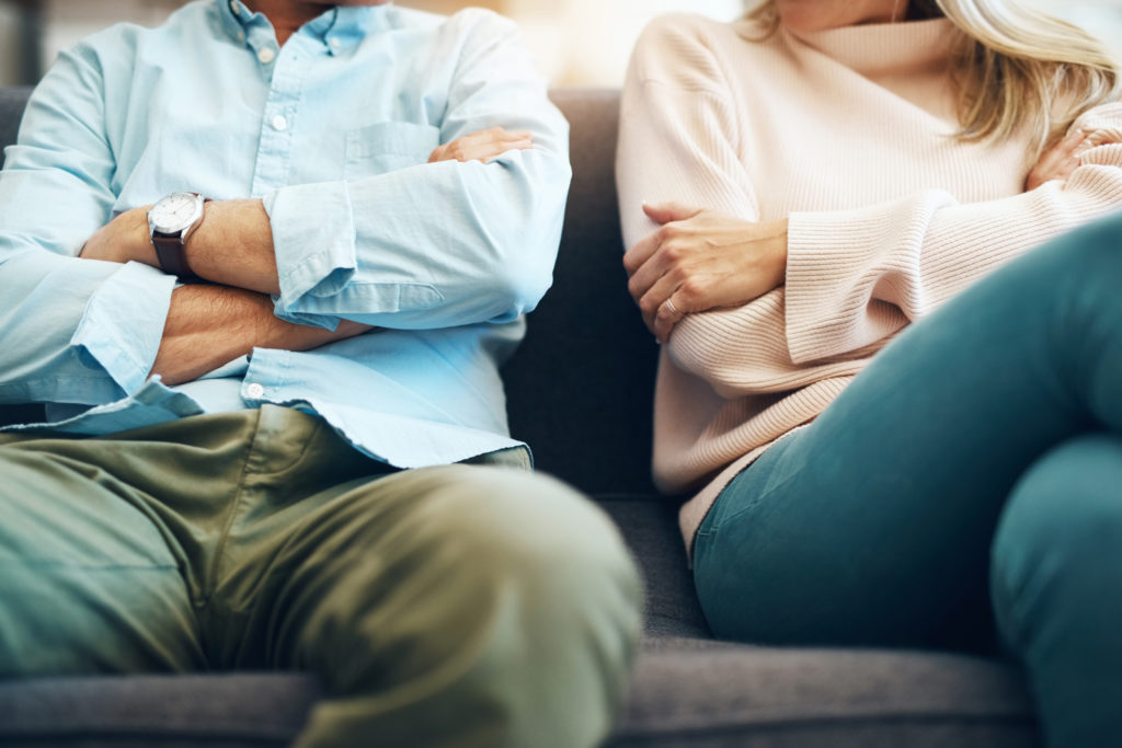 Cropped shot of an unrecognizable mature couple sitting on the sofa with their arms folded after an argument