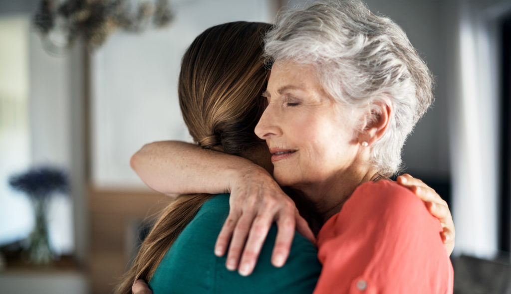 Shot of an elderly woman embracing her daughter at home