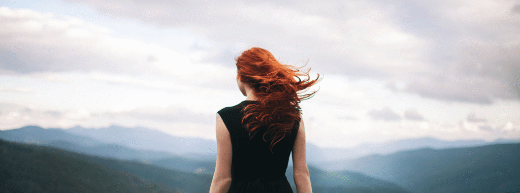 Woman in black dress walking in the mountains and looking at view
