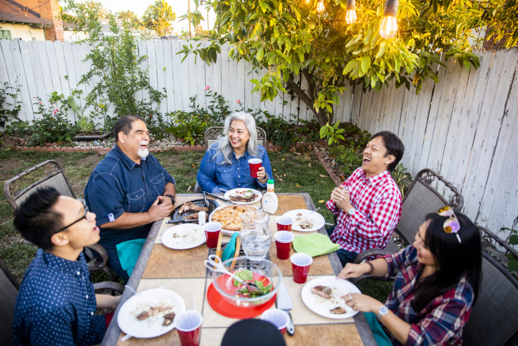 Diverse group of friends having dinner outdoors at a backyard bbq