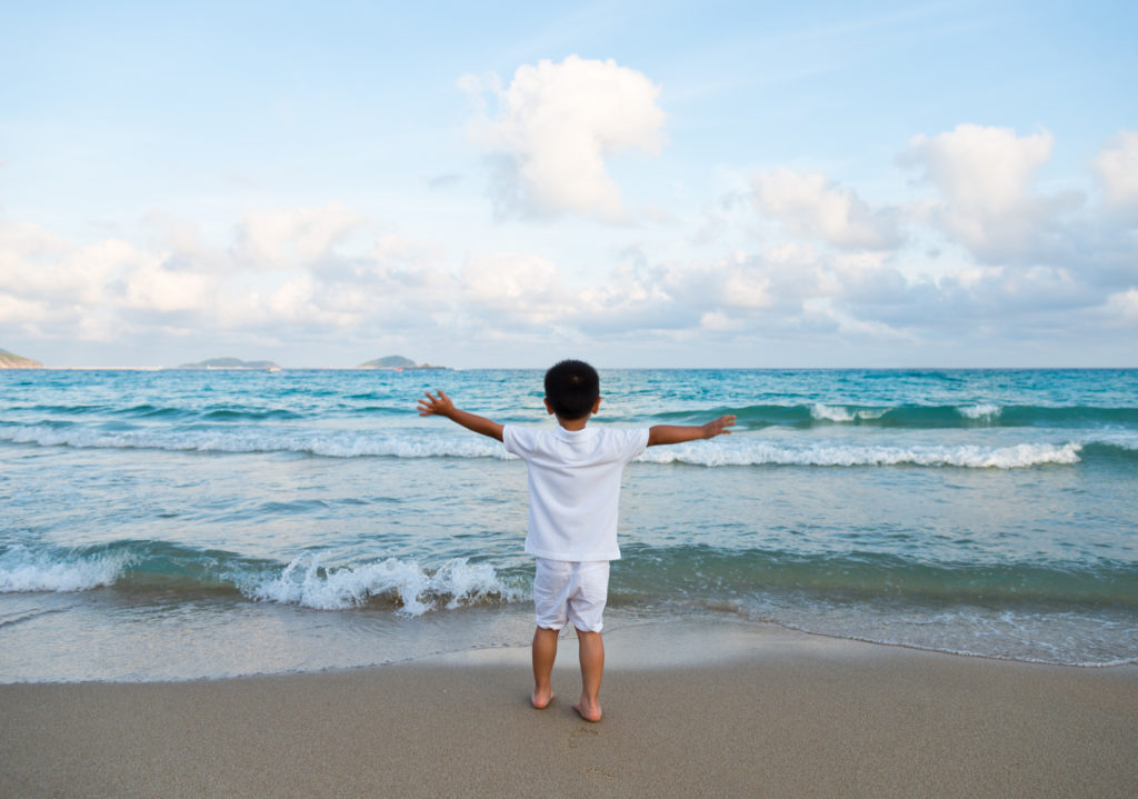 Little boy at the beach, arms outstretched