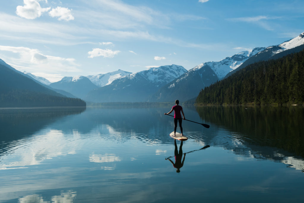Woman stand up paddle boarding on a pristine mountain lake