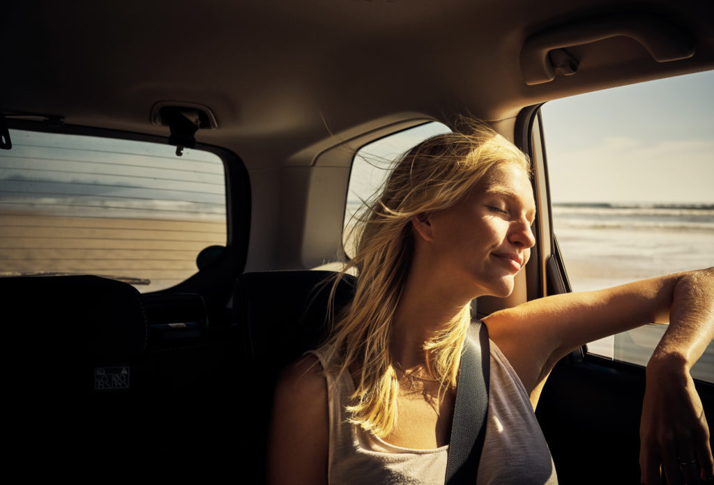 young woman enjoying breeze through open car window