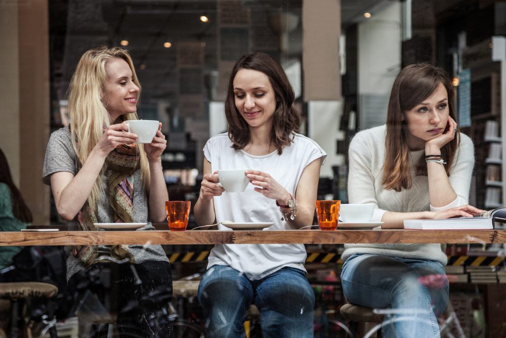 Group of women seated at a cafe's window. toxic friends