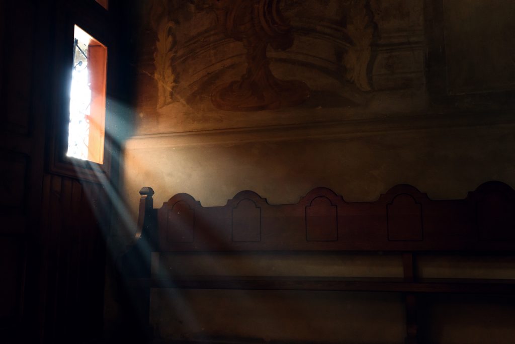 light falling through window in old church on wooden bench