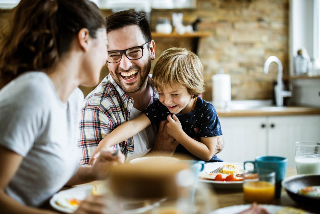 Cheerful family having fun, taking time to laugh during their meal at dining table.